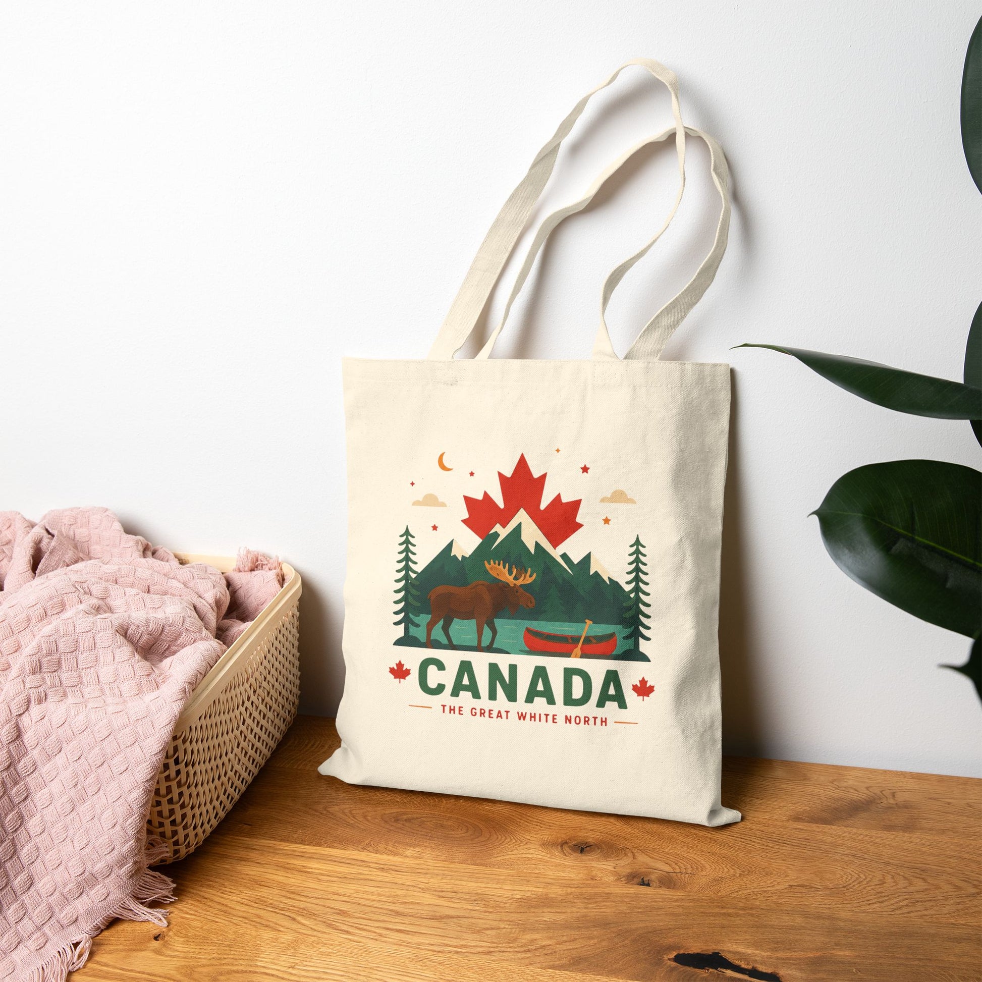 Natural canvas tote bag with Canada moose, trees, and maple graphic on front