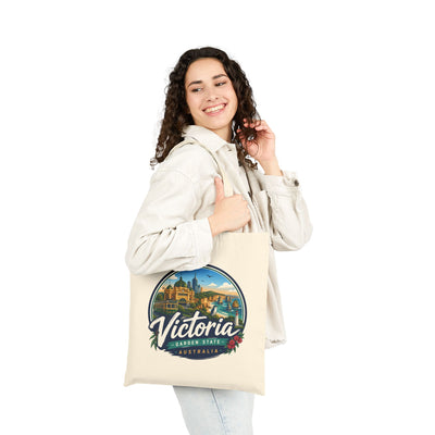 Natural vintage travel tote bag held by a smiling person, circular Victoria Australia logo