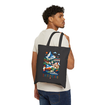 Black canvas tote bag with Switzerland scenic print, carried on a man’s shoulder.