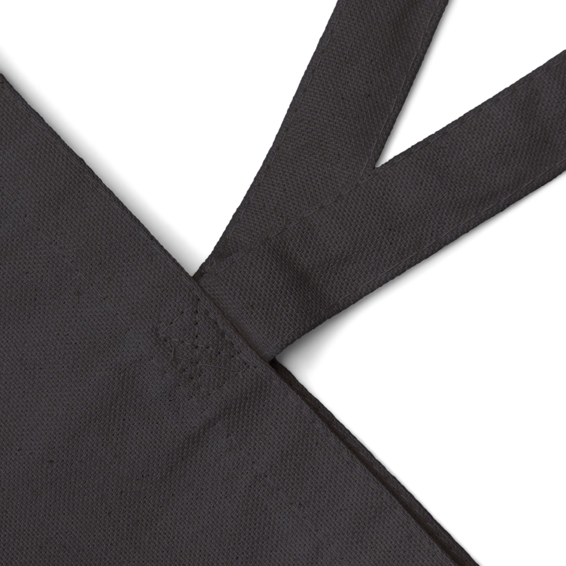 Black canvas tote bag close-up of strap and stitched seam