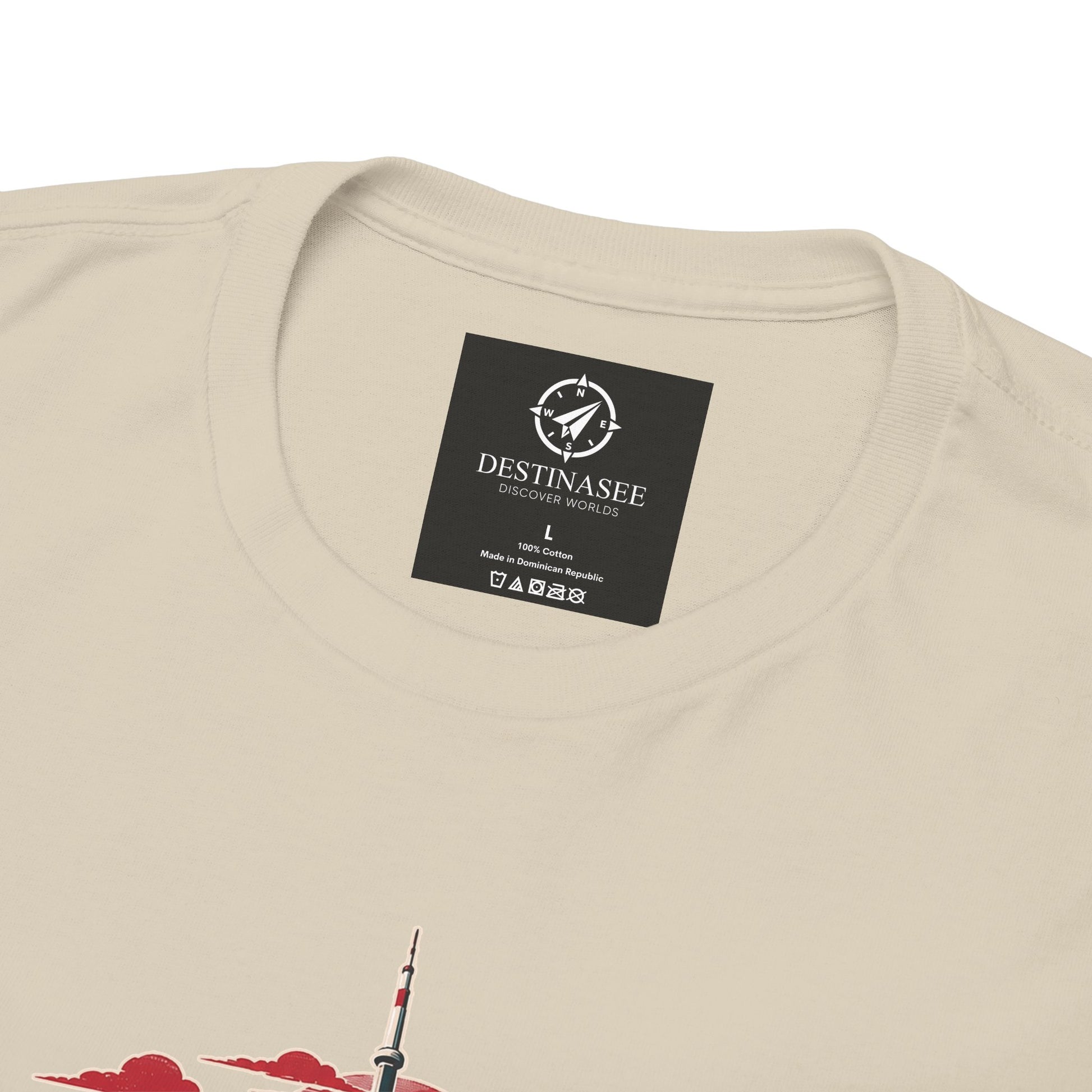 Light tan crew-neck T-shirt with small black neck label and partial skyline graphic