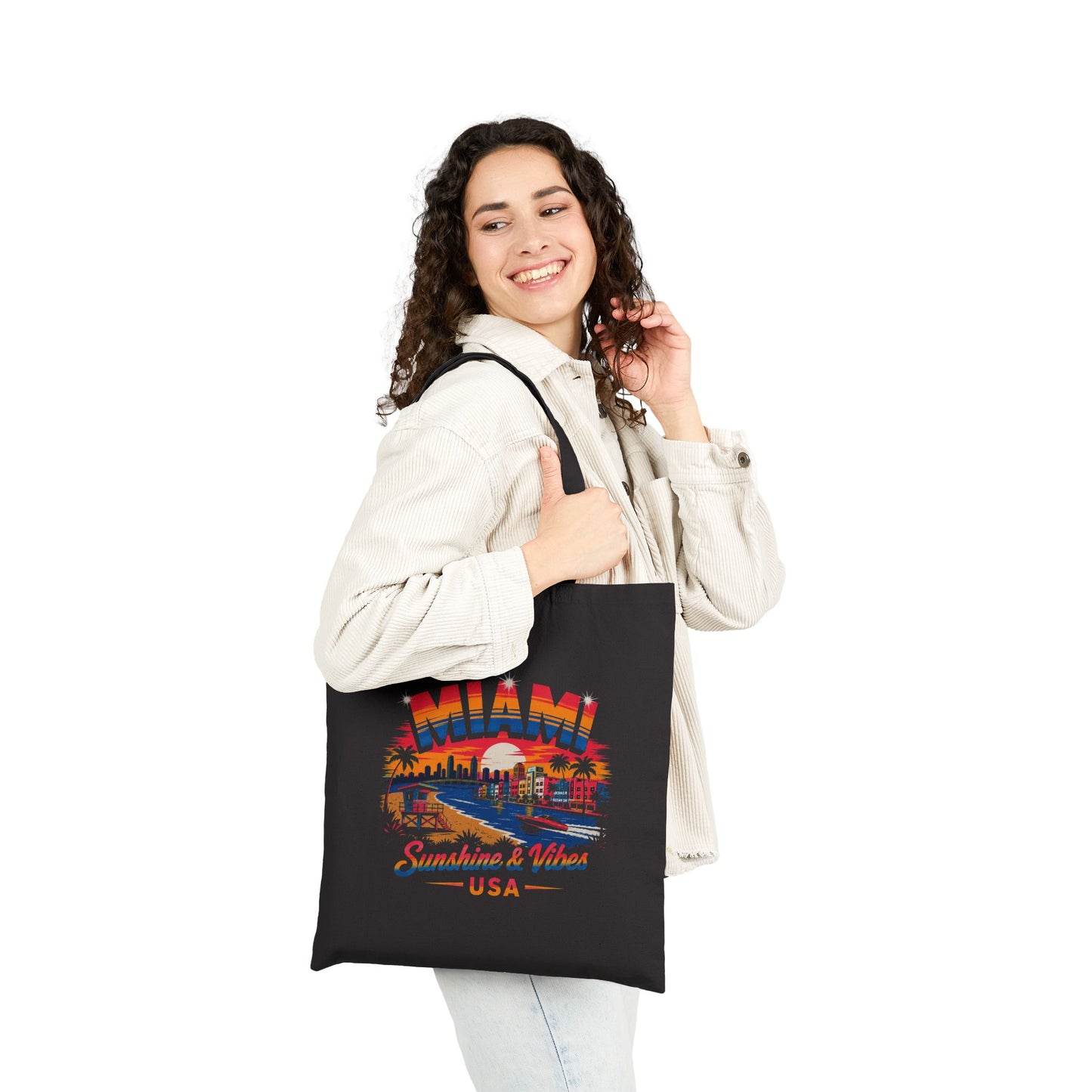 Black tote bag held by a person, featuring Miami skyline graphic
