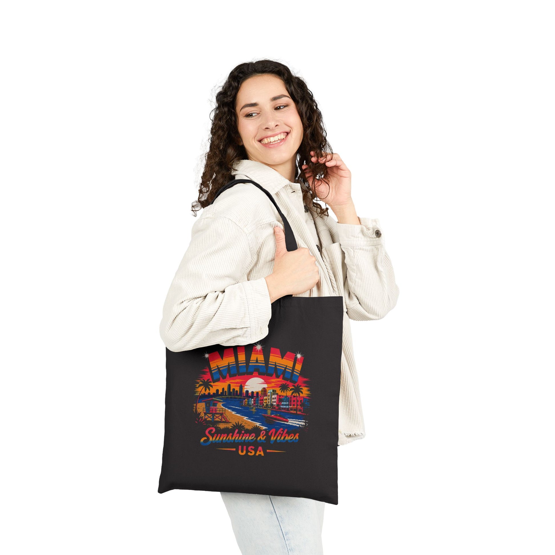 Black tote bag held by a person, featuring Miami skyline graphic