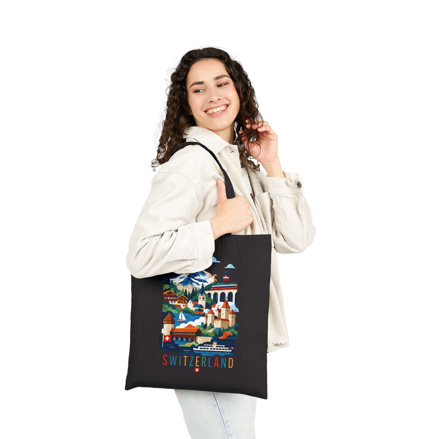 Black canvas tote bag with Switzerland scenic artwork and red “SWITZERLAND” text, worn by a woman.