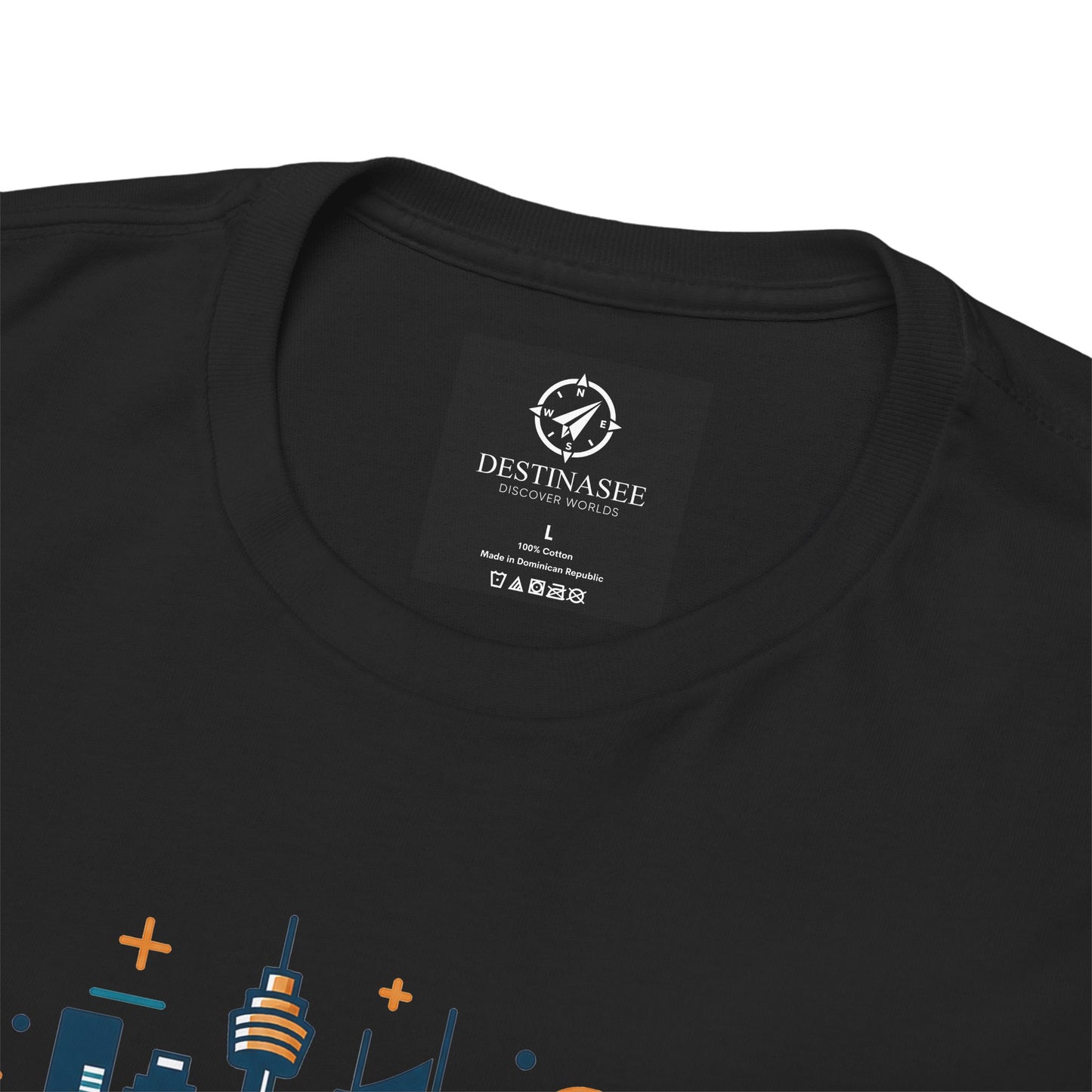 Black T-shirt close-up: round neck label patch with partial colorful Sydney skyline print.