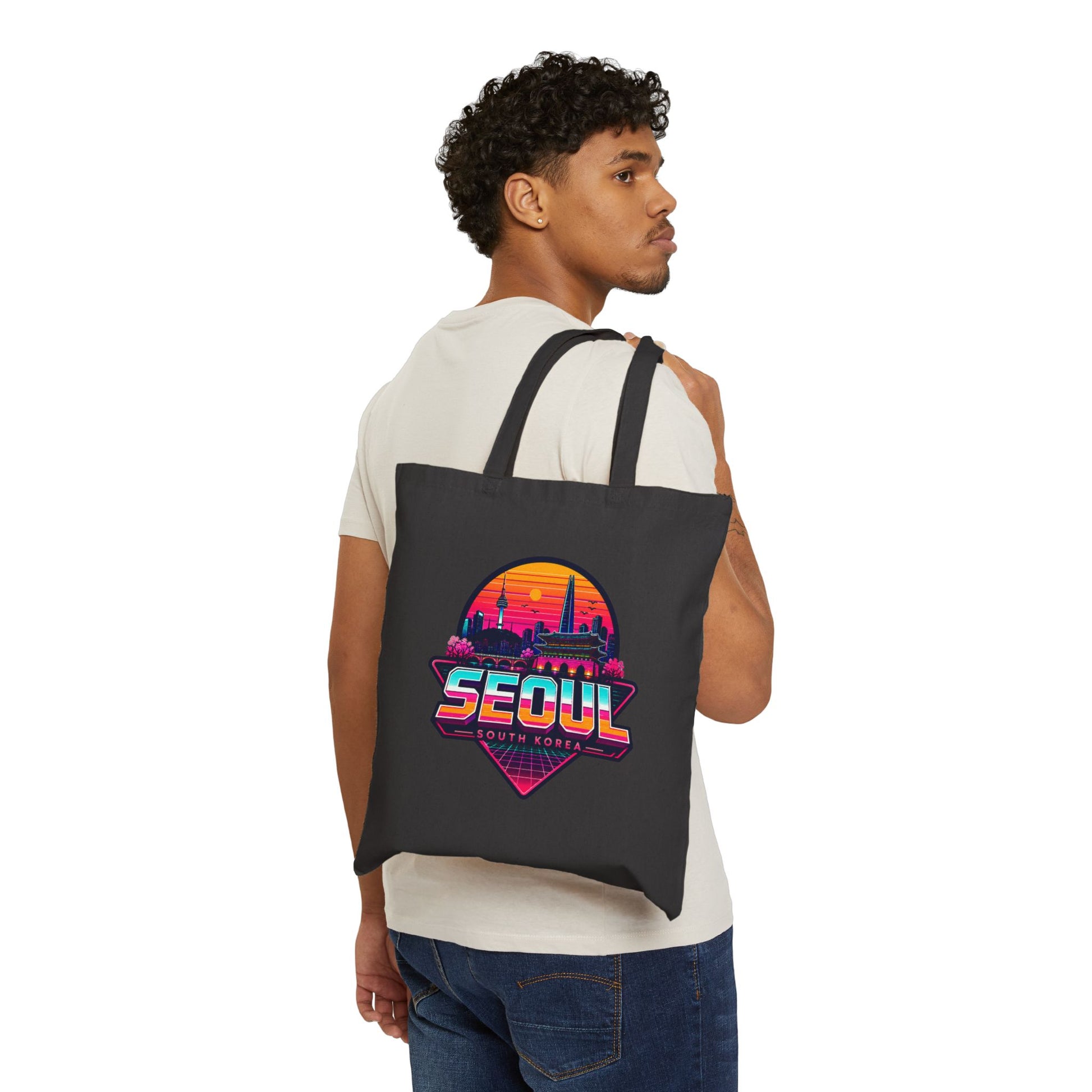 Black tote bag worn by model, front shows colorful Seoul skyline graphic.