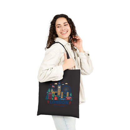 Black canvas tote bag held in hand, London skyline graphic on the front