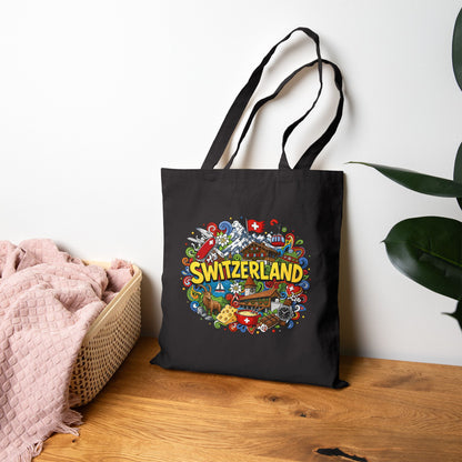 Black canvas tote bag with Switzerland graphic, standing upright on the floor