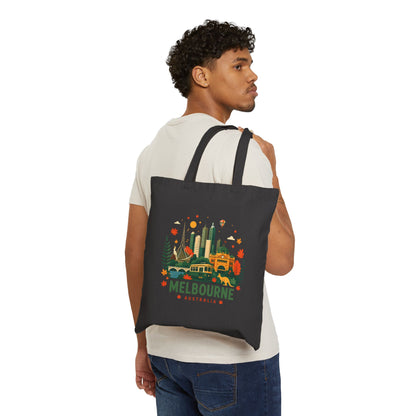 Black canvas tote bag worn over shoulder, front shows Melbourne city graphic.