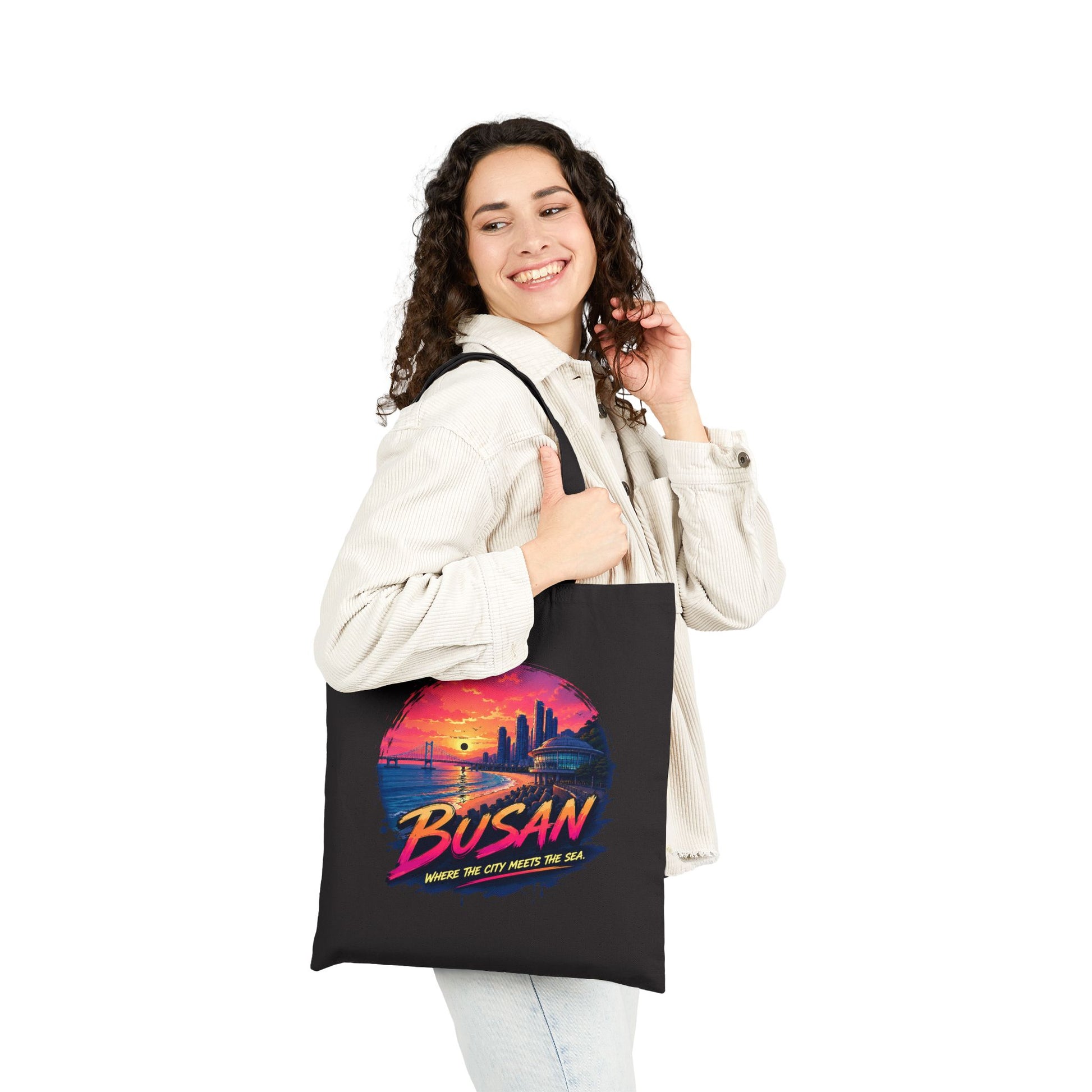 Black canvas tote bag worn on shoulder with front sunset graphic