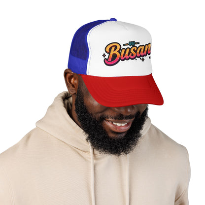 Trucker hat with white front panel and Busan logo, blue mesh sides, red curved brim.