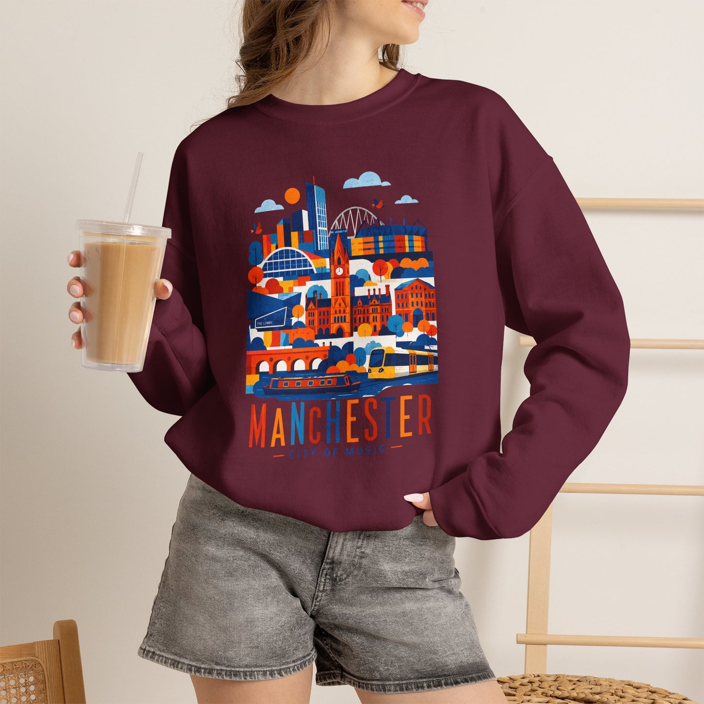 Maroon crewneck sweatshirt with Manchester cityscape graphic print on the front