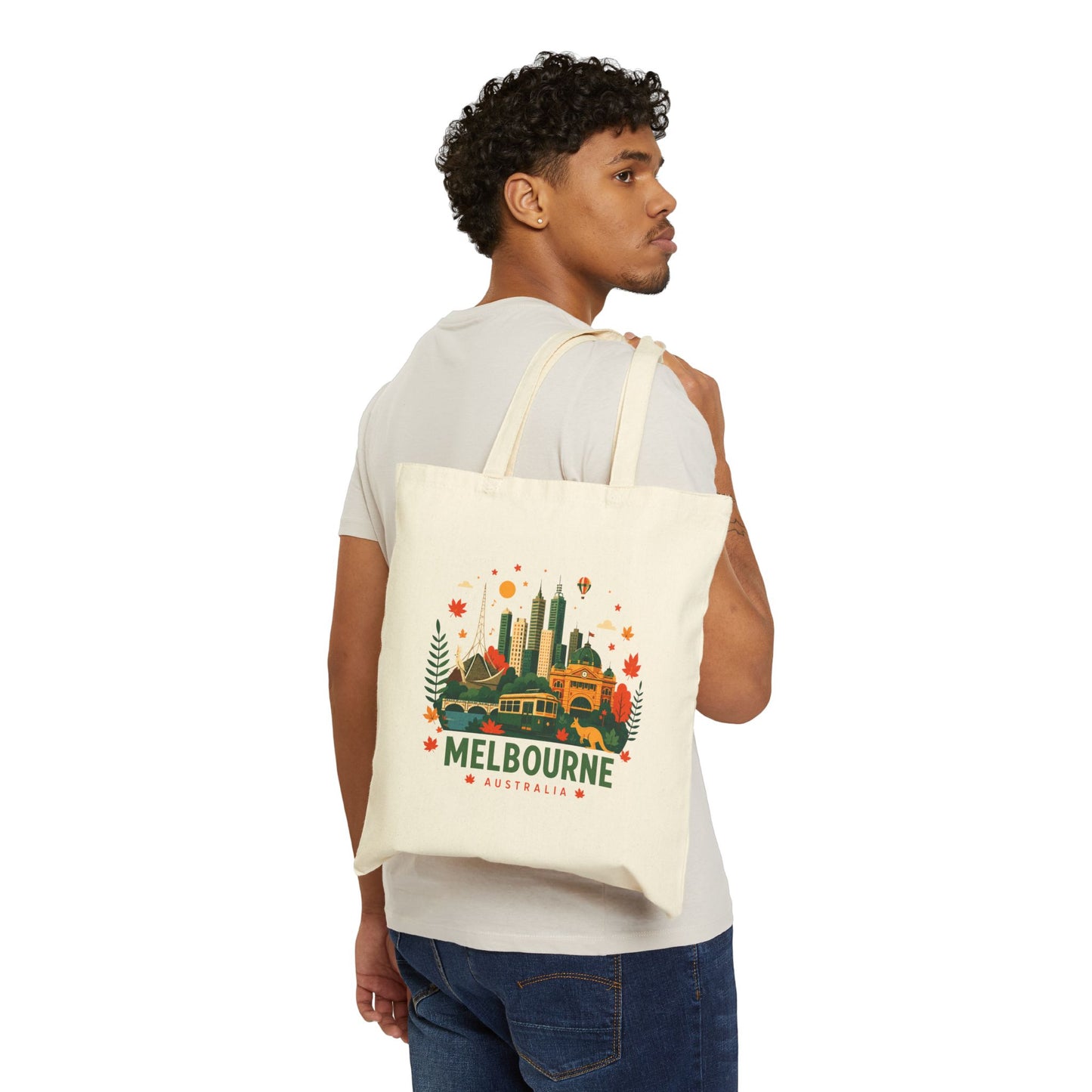 Natural canvas tote bag worn over shoulder, front shows Melbourne city graphic.