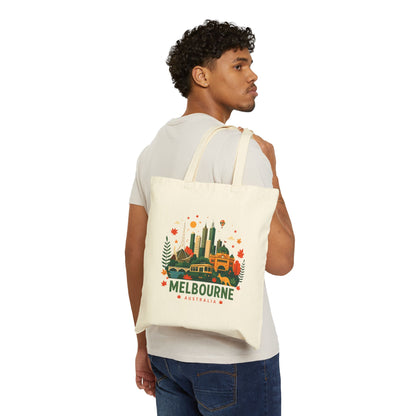 Natural canvas tote bag worn over shoulder, front shows Melbourne city graphic.