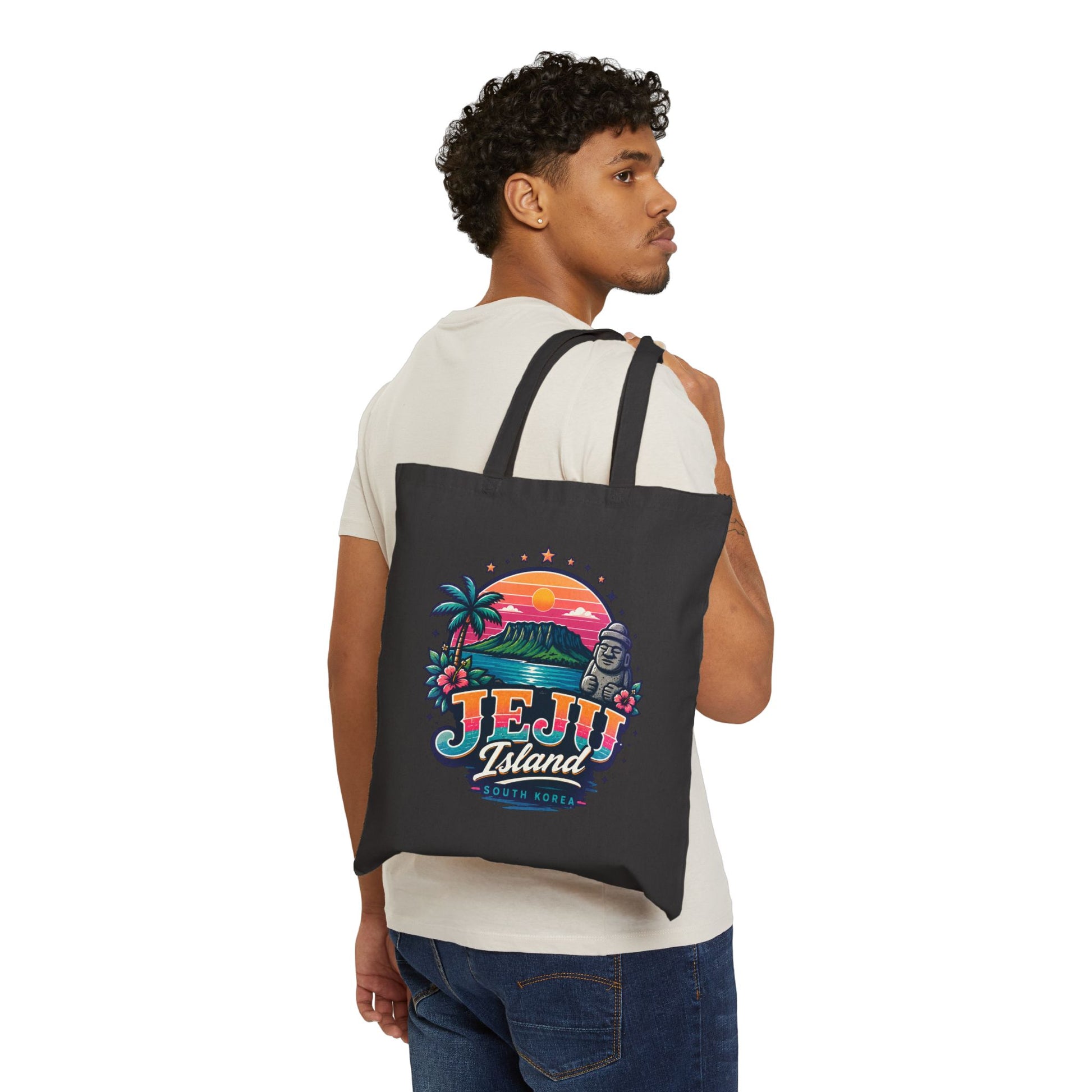 Black canvas tote bag worn on back, featuring colorful Jeju Island front print