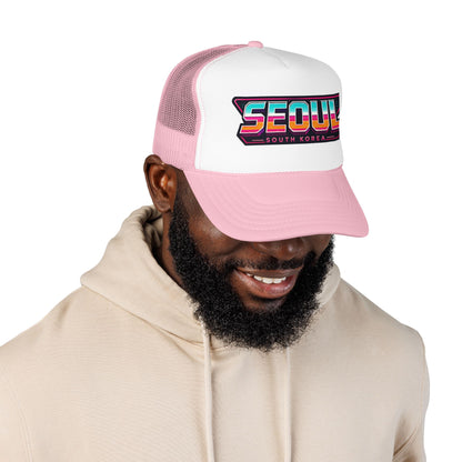 Pink and white trucker hat with “SEOUL SOUTH KOREA” front logo patch on mesh panel.
