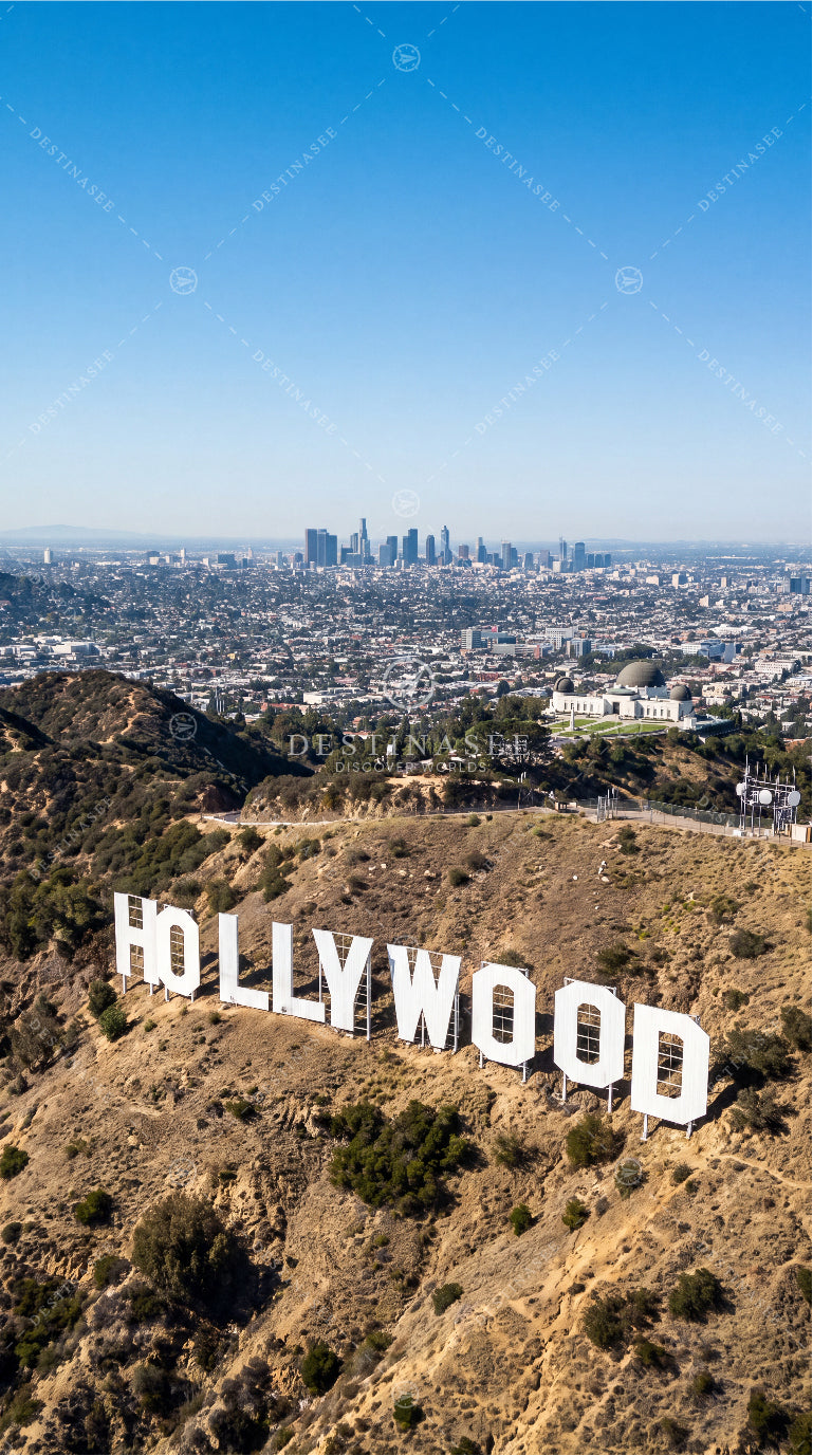 Hollywood sign on grassy hillside with distant city skyline, USA mobile wallpaper