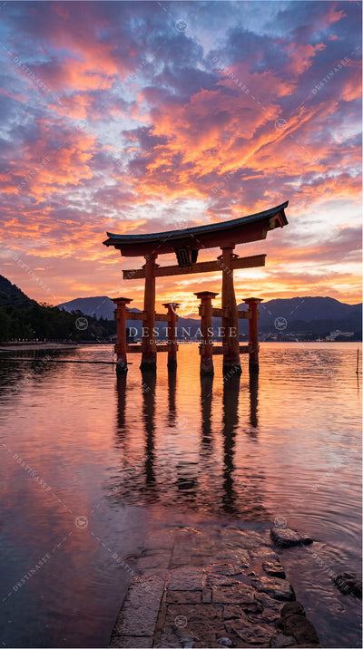 Mobile wallpaper with red torii gate over calm lake at orange-pink sunset